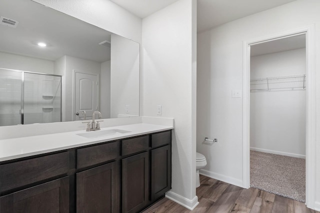 bathroom featuring a stall shower, toilet, visible vents, vanity, and wood finished floors