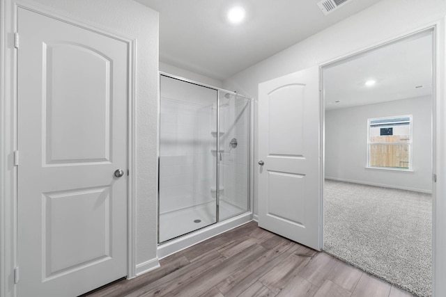 bathroom with a stall shower, recessed lighting, visible vents, and wood finished floors