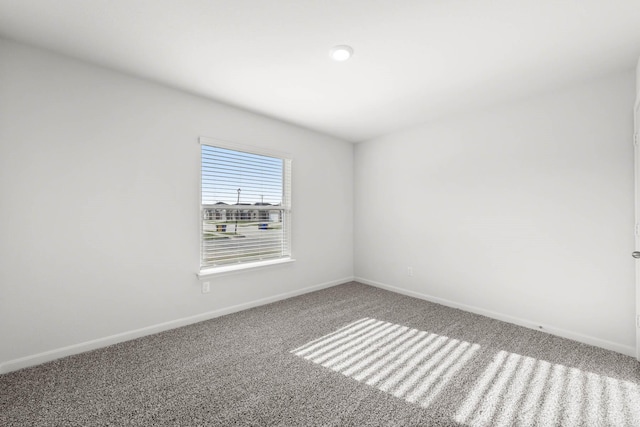 carpeted empty room featuring baseboards
