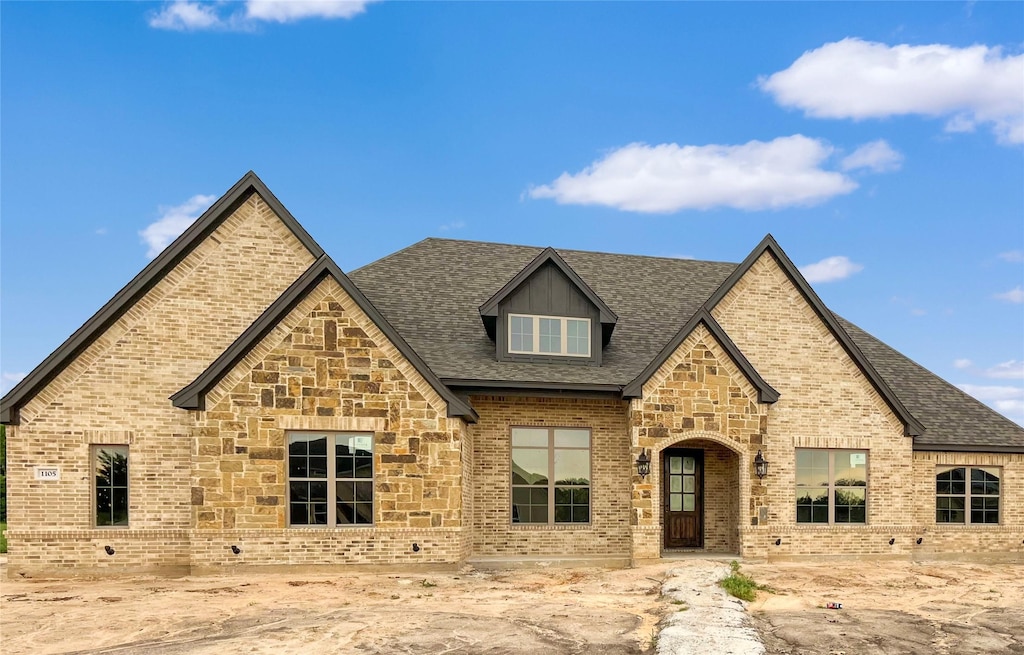 view of front of house with brick siding, roof with shingles, and stone siding