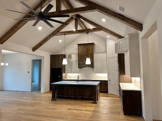 1099 Silver Sage Trl, Weatherford, TX 76085 - kitchen featuring dark brown cabinetry, beamed ceiling, a center island with sink, light wood-style flooring, and a ceiling fan