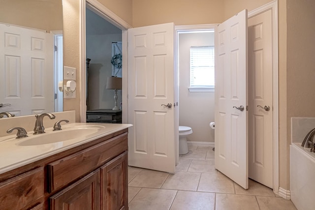 bathroom with toilet, vanity, a tub, tile patterned floors, and baseboards