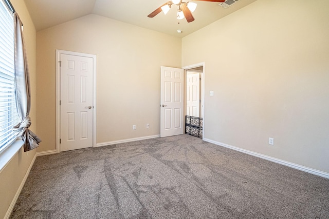unfurnished bedroom featuring lofted ceiling, multiple windows, carpet flooring, and baseboards