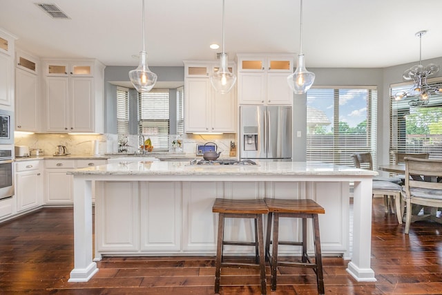 1804 Goodnight Ln, Allen, TX 75002 - kitchen featuring appliances with stainless steel finishes, dark wood finished floors, a kitchen bar, tasteful backsplash, and white cabinets