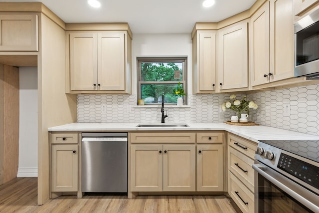 6200 Ravenswood Dr, Fort Worth, TX 76112 - kitchen featuring appliances with stainless steel finishes, a sink, light wood finished floors, light brown cabinets, and recessed lighting