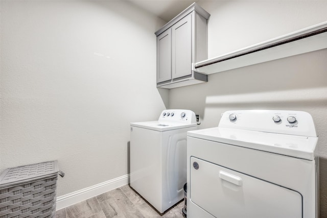 2100 Blackcap St, Denton, TX 76205 - clothes washing area with cabinet space, washing machine and clothes dryer, baseboards, and light wood-style flooring