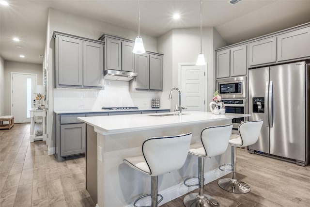 2100 Blackcap St, Denton, TX 76205 - kitchen featuring gray cabinetry, under cabinet range hood, a sink, light countertops, and appliances with stainless steel finishes