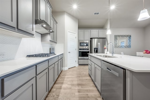 2100 Blackcap St, Denton, TX 76205 - kitchen with a sink, appliances with stainless steel finishes, backsplash, gray cabinetry, and light wood-style floors