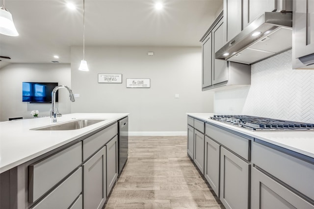 2100 Blackcap St, Denton, TX 76205 - kitchen featuring a sink, wall chimney exhaust hood, light wood-type flooring, backsplash, and gray cabinetry