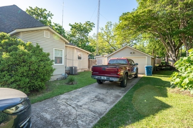 1501 W Crawford St W, Denison, TX 75020 - view of home's exterior featuring a detached garage, an outdoor structure, a lawn, and central AC