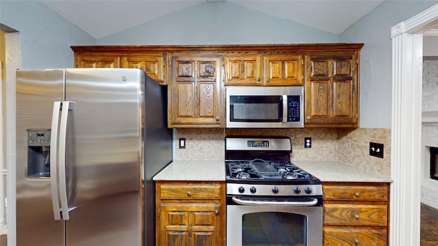 10020 Richard Cir, Forney, TX 75126 - kitchen featuring vaulted ceiling, stainless steel appliances, brown cabinets, and tasteful backsplash