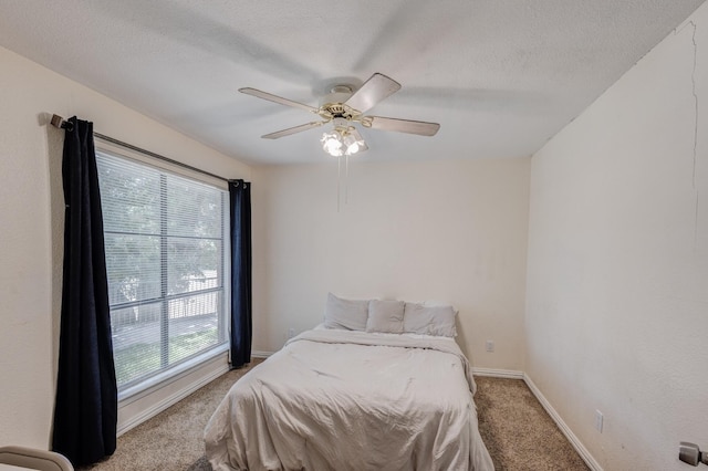 bedroom featuring baseboards, light carpet, ceiling fan, and a textured ceiling