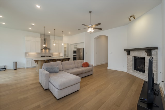 9415 Royal Forest Dr, Oak Point, TX 75068 - living room with arched walkways, light wood-type flooring, ceiling fan, a fireplace, and recessed lighting