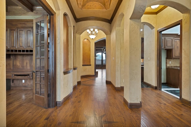 1206 Genesis Dr, Mansfield, TX 76063 - hallway with arched walkways, crown molding, dark wood-style flooring, a textured wall, and a chandelier