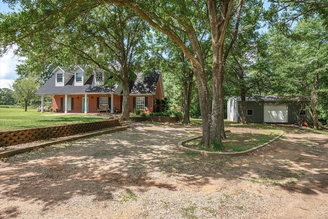200 County Road 1574, Alba, TX 75410 - cape cod house featuring covered porch, an outdoor structure, brick siding, a front lawn, and dirt driveway