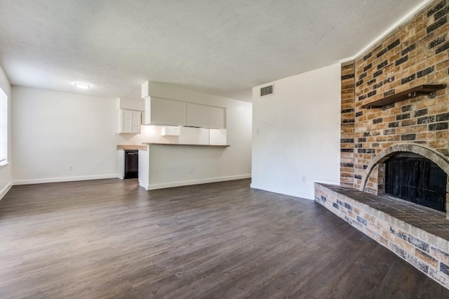 2210 Sheriff Dr, Grand Prairie, TX 75051 - unfurnished living room featuring baseboards, dark wood-style floors, a brick fireplace, and a textured ceiling