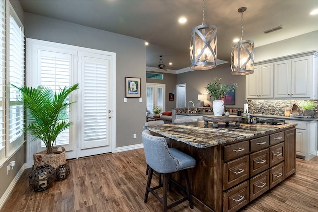 3528 Clubgate Dr, Fort Worth, TX 76137 - kitchen featuring dark brown cabinets, a breakfast bar, visible vents, and wood finished floors