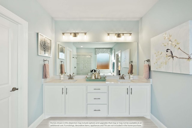 full bath featuring a sink, double vanity, a stall shower, and baseboards
