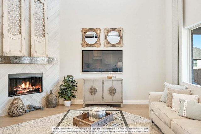 living area with baseboards, a glass covered fireplace, and wood finished floors