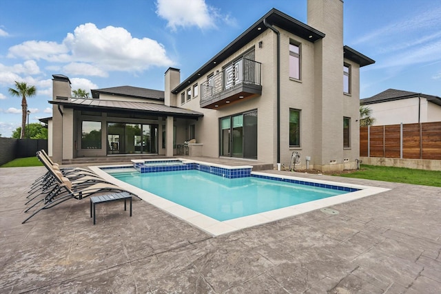 rear view of property with a fenced backyard, a chimney, a standing seam roof, and a balcony