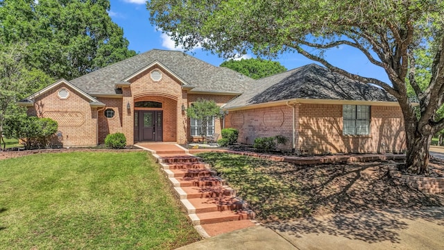 ranch-style home with brick siding, roof with shingles, and a front yard