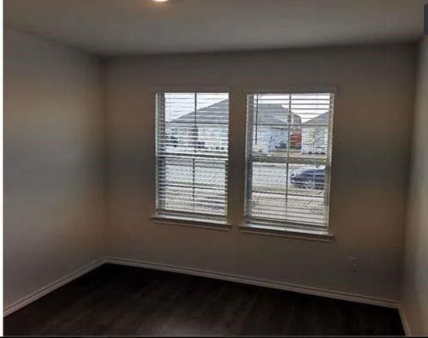 unfurnished room with dark wood-type flooring and baseboards