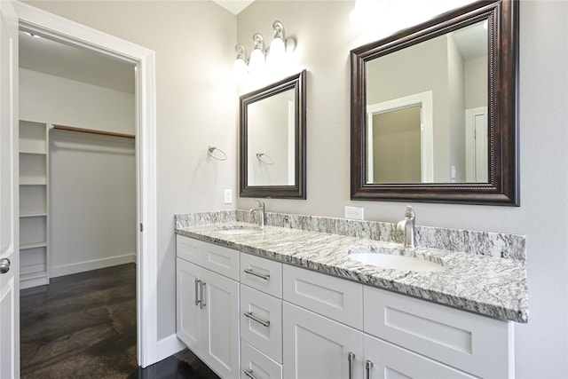 250 Martis Way, Abilene, TX 79602 - full bathroom featuring double vanity, baseboards, a walk in closet, and a sink