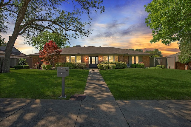 ranch-style home with a yard and brick siding
