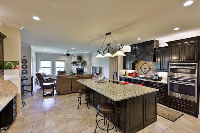 8301 Cimarron Trl, Abilene, TX 79606 - kitchen featuring a sink, a breakfast bar, ornamental molding, stainless steel double oven, and a fireplace