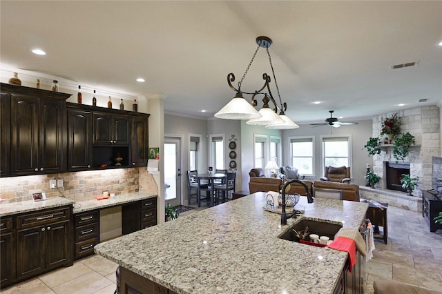 8301 Cimarron Trl, Abilene, TX 79606 - kitchen with a sink, tasteful backsplash, a kitchen island with sink, visible vents, and a fireplace