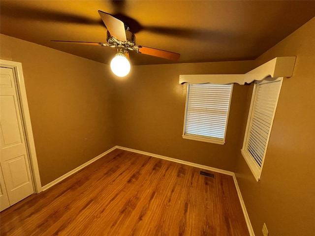 empty room with wood finished floors, baseboards, and ceiling fan