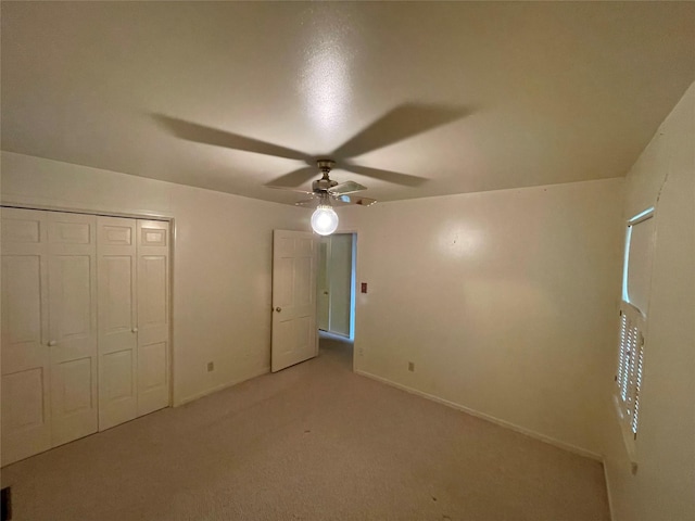 unfurnished bedroom with ceiling fan, light carpet, a closet, and baseboards
