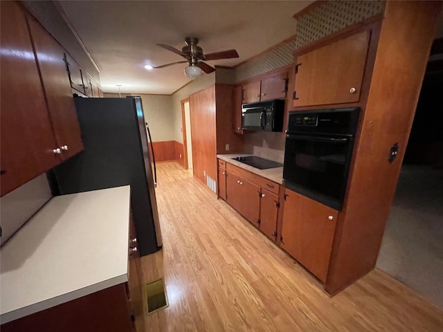 kitchen with black appliances, light wood-style flooring, a ceiling fan, light countertops, and brown cabinets