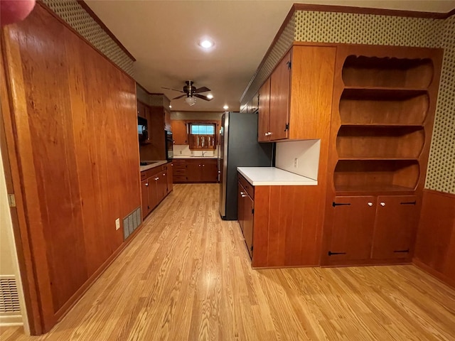 kitchen with a ceiling fan, brown cabinets, light countertops, light wood-type flooring, and oven