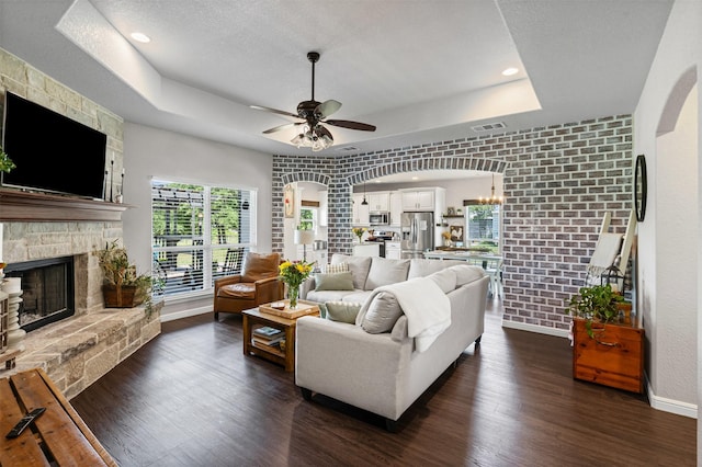 6093 S Fm 730, Decatur, TX 76234 - living area featuring a raised ceiling, dark wood-style floors, a fireplace, a ceiling fan, and baseboards