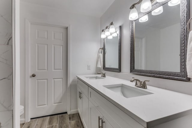 bathroom featuring double vanity, wood finished floors, and a sink