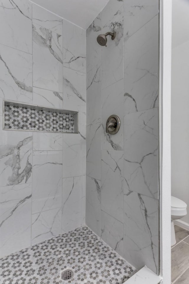 bathroom with toilet and a tile shower