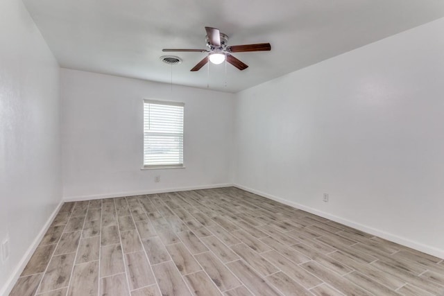 spare room featuring light wood-style floors, visible vents, baseboards, and a ceiling fan