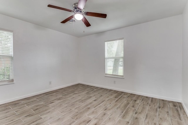 spare room featuring light wood finished floors, baseboards, and a ceiling fan