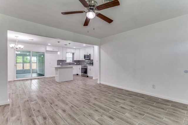 unfurnished living room with light wood-style floors, baseboards, ceiling fan with notable chandelier, and recessed lighting