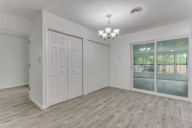 unfurnished dining area with baseboards, light wood-style floors, an inviting chandelier, and visible vents