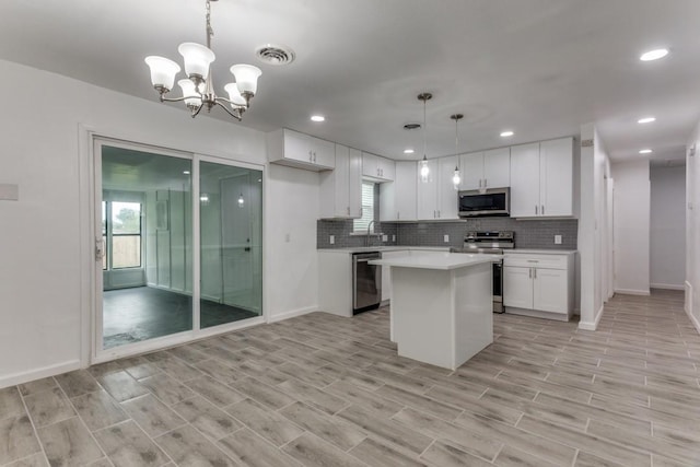 kitchen with a notable chandelier, stainless steel appliances, backsplash, light countertops, and white cabinets