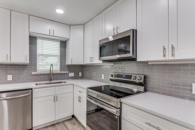 kitchen featuring white cabinets, light countertops, stainless steel appliances, and a sink