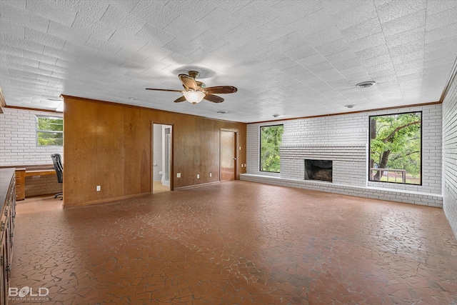 unfurnished living room with crown molding, a wealth of natural light, a fireplace, and ceiling fan