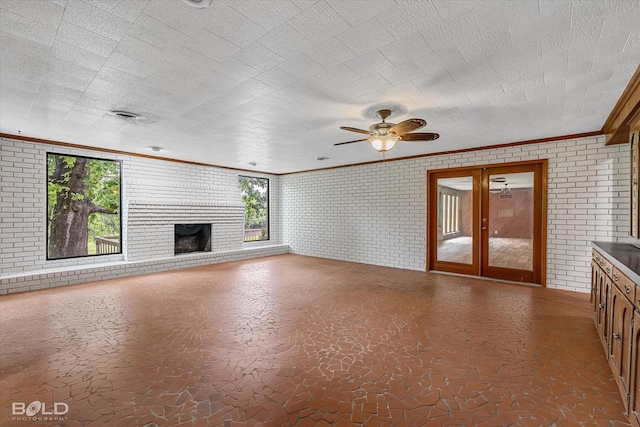 5764 Jefferson Paige Rd, Shreveport, LA 71119 - unfurnished living room with ornamental molding, brick wall, a fireplace, ceiling fan, and french doors