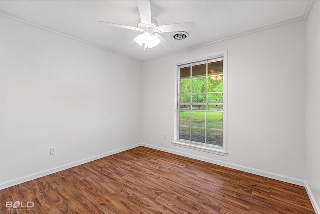 empty room with wood finished floors, visible vents, baseboards, ceiling fan, and ornamental molding