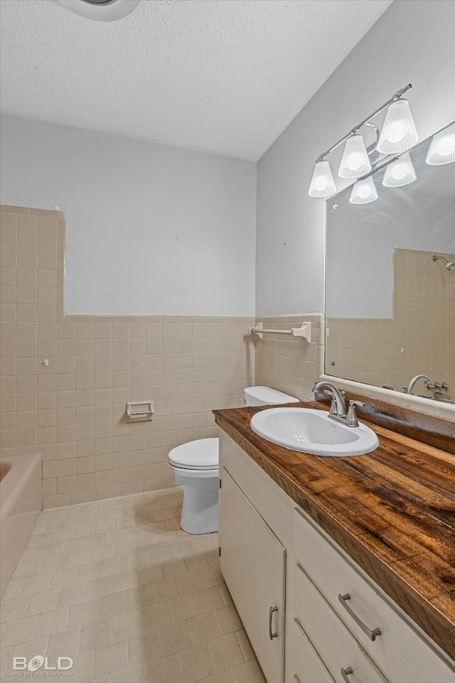 full bathroom with tile walls, toilet, a shower, vanity, and tile patterned floors