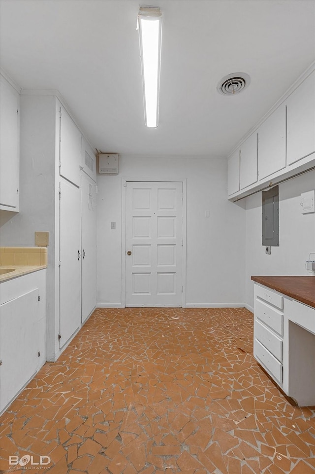 kitchen with baseboards, white cabinets, visible vents, and electric panel
