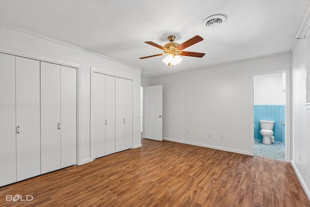 5764 Jefferson Paige Rd, Shreveport, LA 71119 - unfurnished bedroom featuring multiple closets, wood finished floors, connected bathroom, crown molding, and a textured ceiling