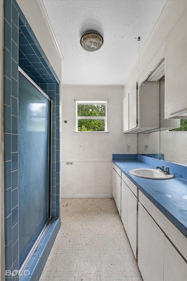 full bath featuring vanity, a textured ceiling, tile patterned floors, a stall shower, and baseboards